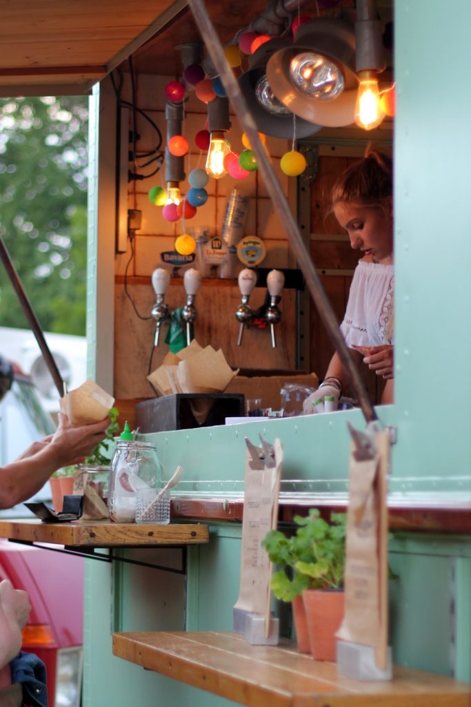 young food truck worker stands in colorful food truck scanning customer's credit card