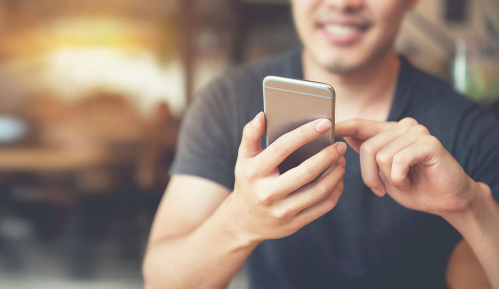 photo of a man looking down at his smartphone and smiling