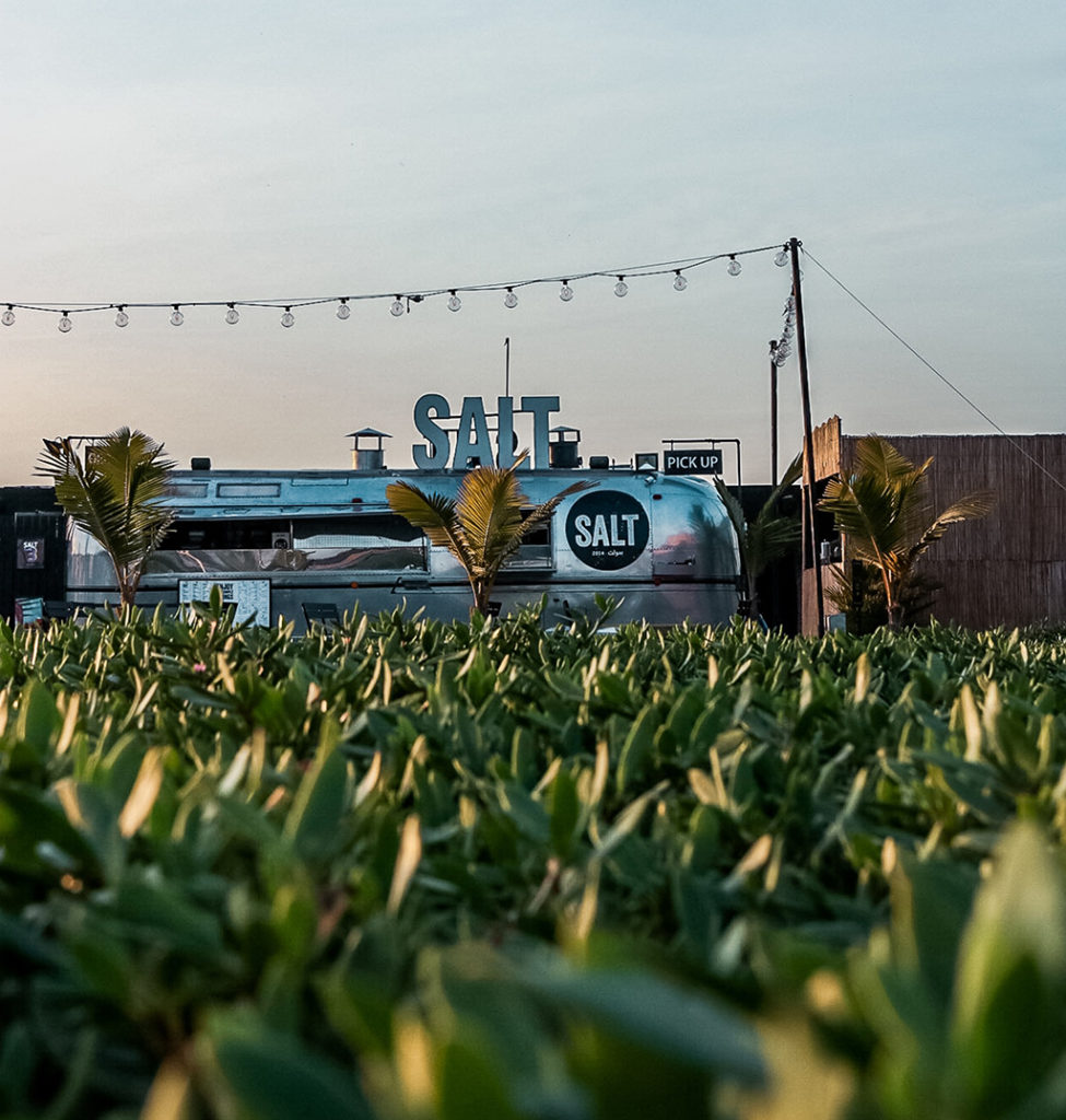 silver food truck parked near a field at sunset