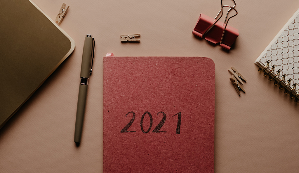 photo of a desk with office supplies and a red notebook with "2021" on the cover