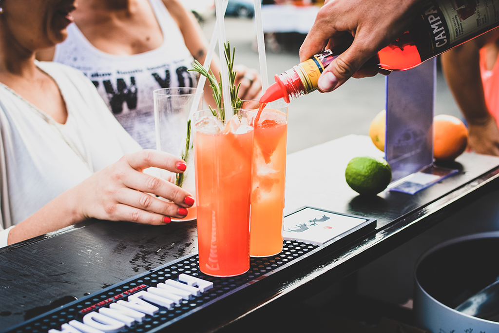 bartender pouring orange liquid into a cocktail glass