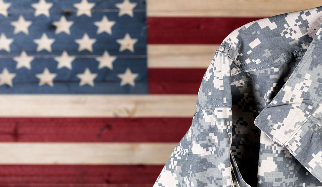 Close up of military uniform with painted rustic boards of USA flag in background.